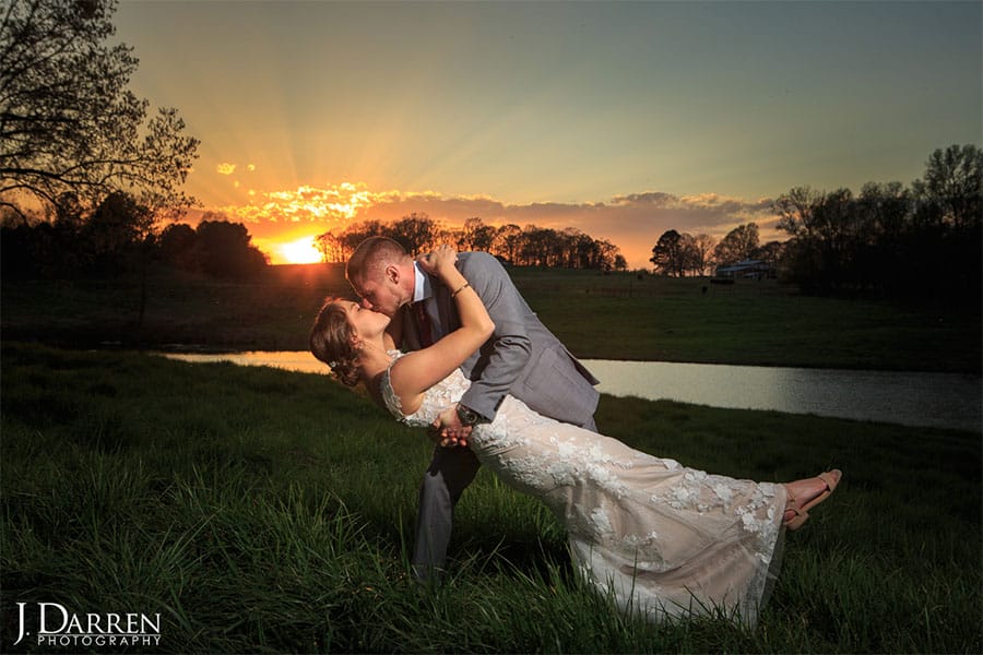 The bride and groom kissing with the sunset in the background.
