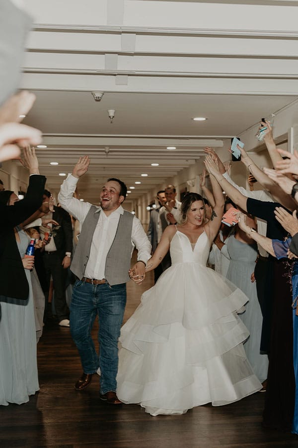 The bride and groom leaving with their friends and family beside them.