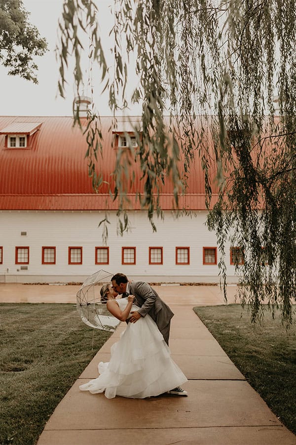 The bride and groom are kissing in front of a building.