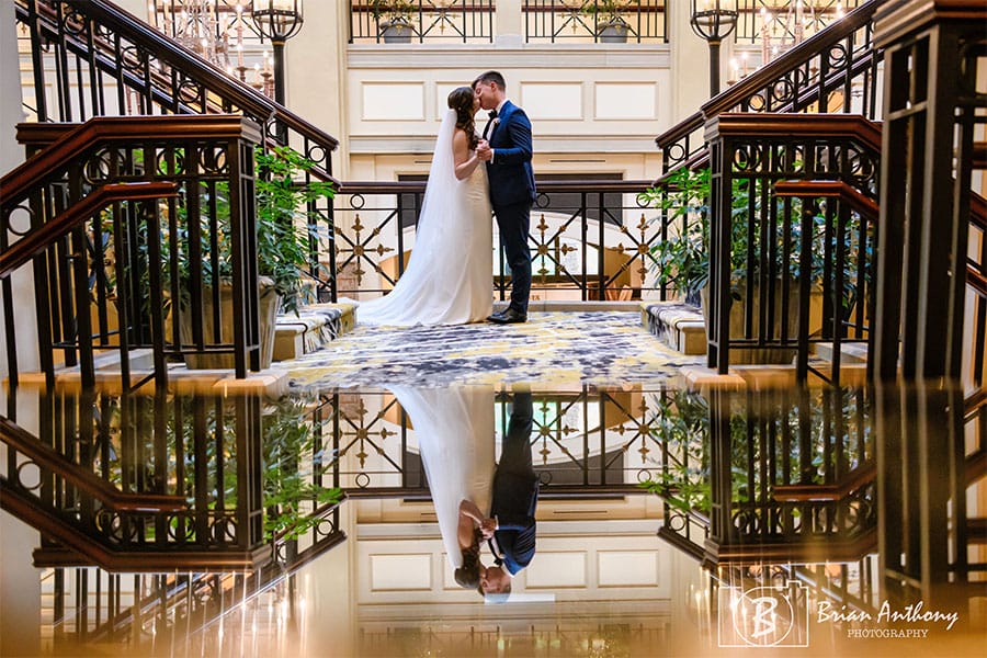 The bride and groom kissing with a reflection of them being shown.