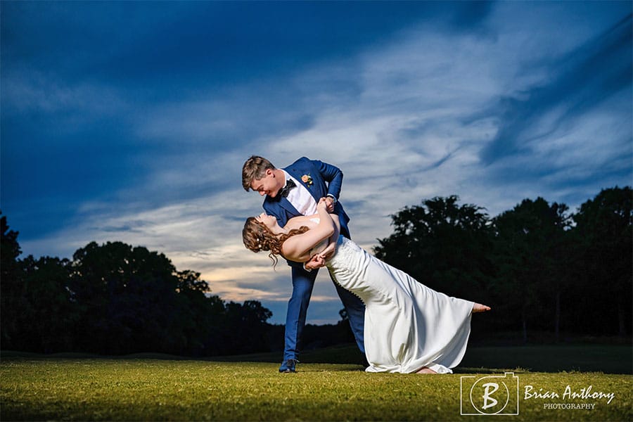 The groom holding the bride in a beautiful field.