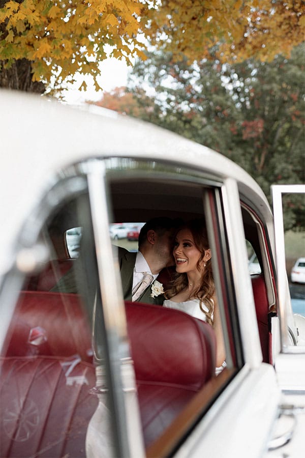 The bride and groom sitting in the back of a car.