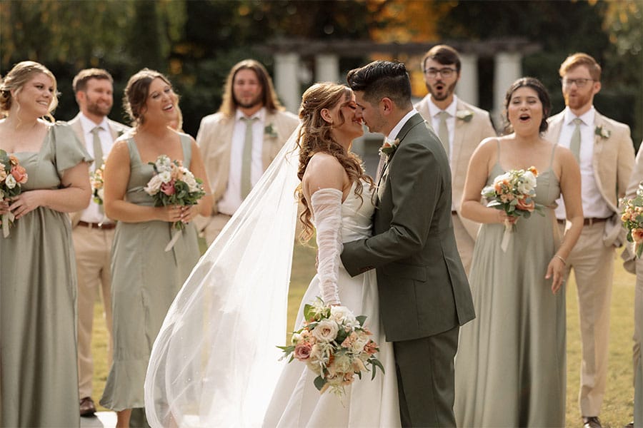 The bride and groom looking at eachother with the bridesmaids and groomsmen in the back.