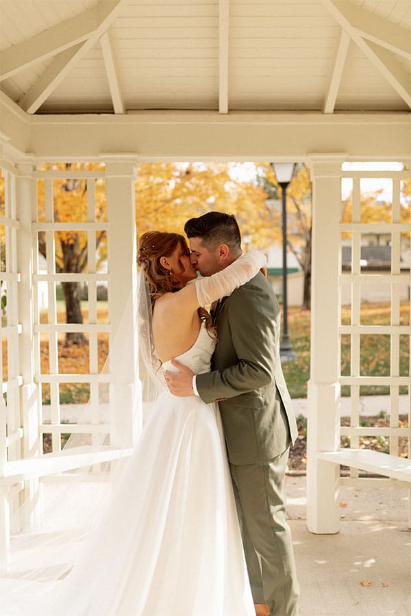 The bride and groom kissing in a gazebo.