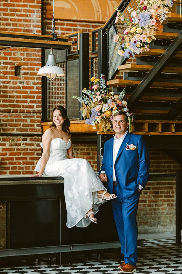 The bride sitting and the groom standing.