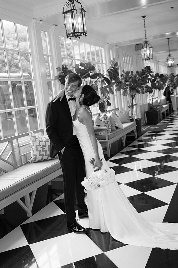 The bride kissing the groom on the cheek.