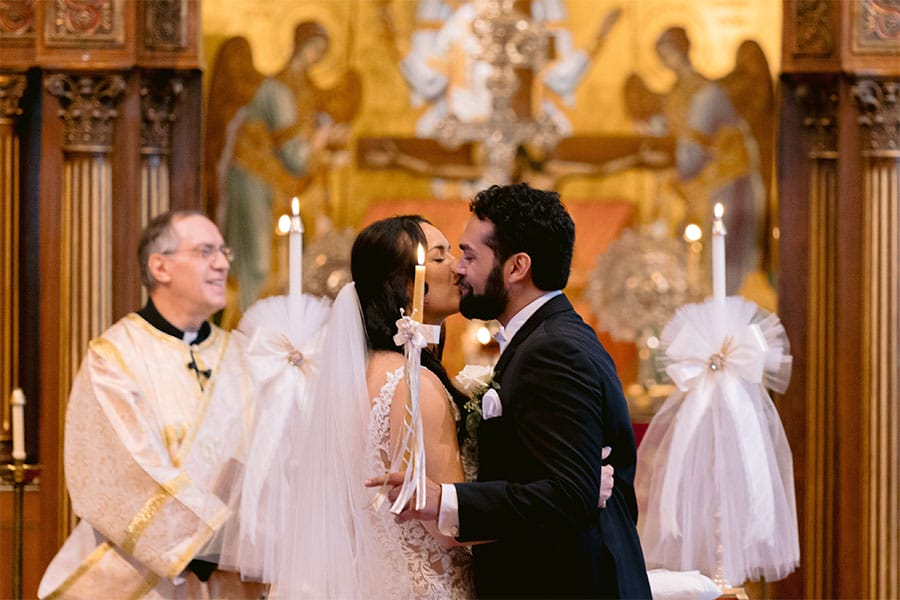 The bride and groom kissing with candles around them.