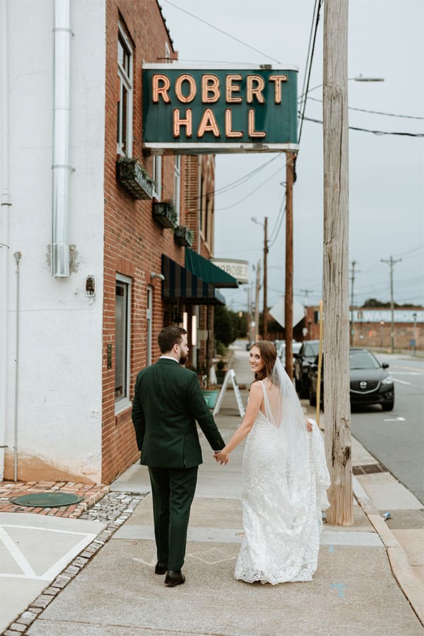 The bride and groom holding hands walking down the street.
