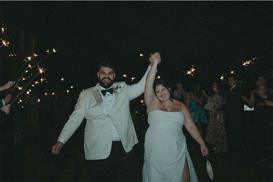 The bride and groom holding hands with lights in the background.