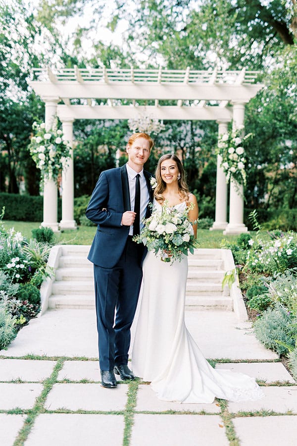 The bride and groom in front of a beautiful garden.
